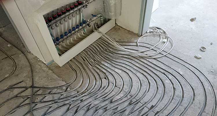 Foto: Gefliester Wand- und Bodenbereich in einer Ecke, in dem mehrere Wandfliesen beschädigt oder komplett entfernt sind. Darunter sind bröckelnder Putz und freigelegte, unregelmäßige Mörtelschichten erkennbar.  