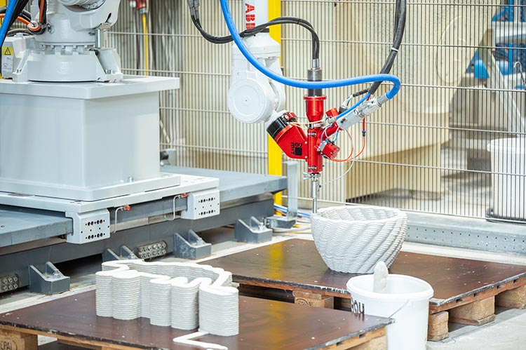 Das Bild zeigt einen 3-D-Drucker, der eine schalenartige Form aus Beton gedruckt hat. 