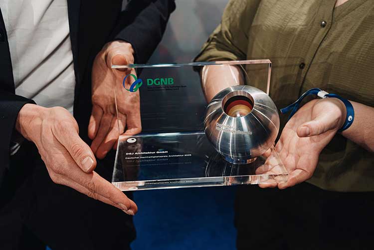 Das Bild zeigt die Hände von zwei Personen, die die Preisstatuette des Deutschen Nachhaltigkeitspreises Architektur halten. 