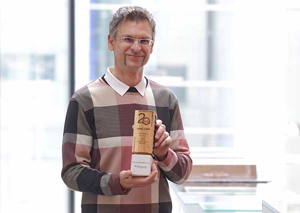 Das Bild zeigt den Preisträger Dipl.-Ing. (FH) Ingo Kern, ö.b.u.v. Sachverständiger für Schäden an Gebäuden mit seiner Preisstatuette aus Holz.