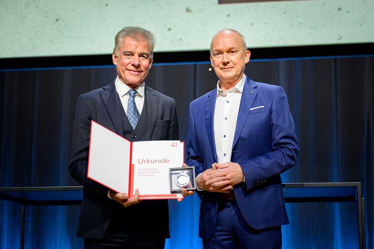 Das Bild zeigt Professor Konrad Bergmeister (links), der von dem DBV-Vorsitzenden Dr. Matthias Jacob die Emil-Mörsch-Denkmünze und eine Urkunde überreicht bekommen hat und sie mit einem Lächeln präsentiert. 