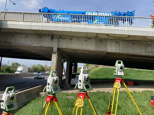 Das Bild zeigt die Laxenburger Brücke in Wien, an der verschiedene Sensortechnologien eingesetzt wurden, darunter drahtlose Sensoren zur Überwachung von Neigungen und Rissbreiten sowie faseroptische Systeme zur hochauflösenden Dehnungsmessung und Rissdetektion unter Verkehrsbelastung (für die Tests wurde auch der im Bild gezeigte Kranwagen eingesetzt).