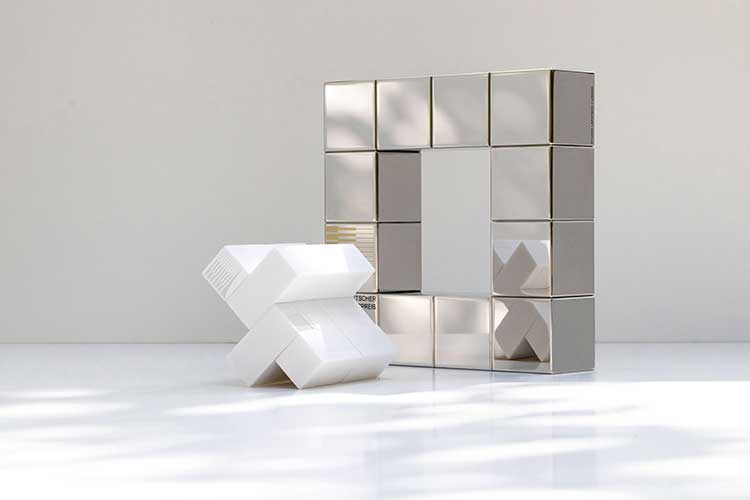 Links eine weiße, x-förmige Struktur mit rechteckigen Elementen. Rechts eine quadratische Metallskulptur mit spiegelnden Oberflächen und einer zentralen Aussparung in der Mitte. 