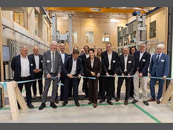 Gruppe von Personen in Geschäftskleidung bei einer Banddurchtrennung in einer modernen Halle, als feierliche Eröffnung einer Einrichtung. 