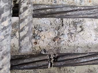 Betonoberfläche mit mehreren horizontal verlaufenden Bewehrungsstäben, von denen ein Bündel mittig sichtbar beschädigt oder unterbrochen ist 