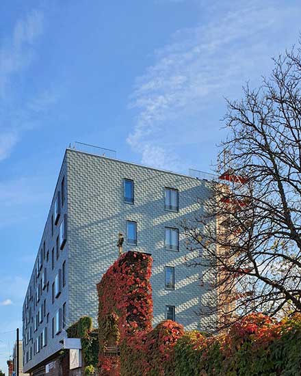 Mehrstöckiges Gebäude mit moderner, grauer Holzfassade. 