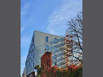 Mehrstöckiges Gebäude mit moderner, grauer Holzfassade. 