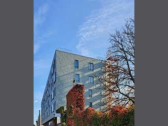 Mehrstöckiges Gebäude mit moderner, grauer Holzfassade. 